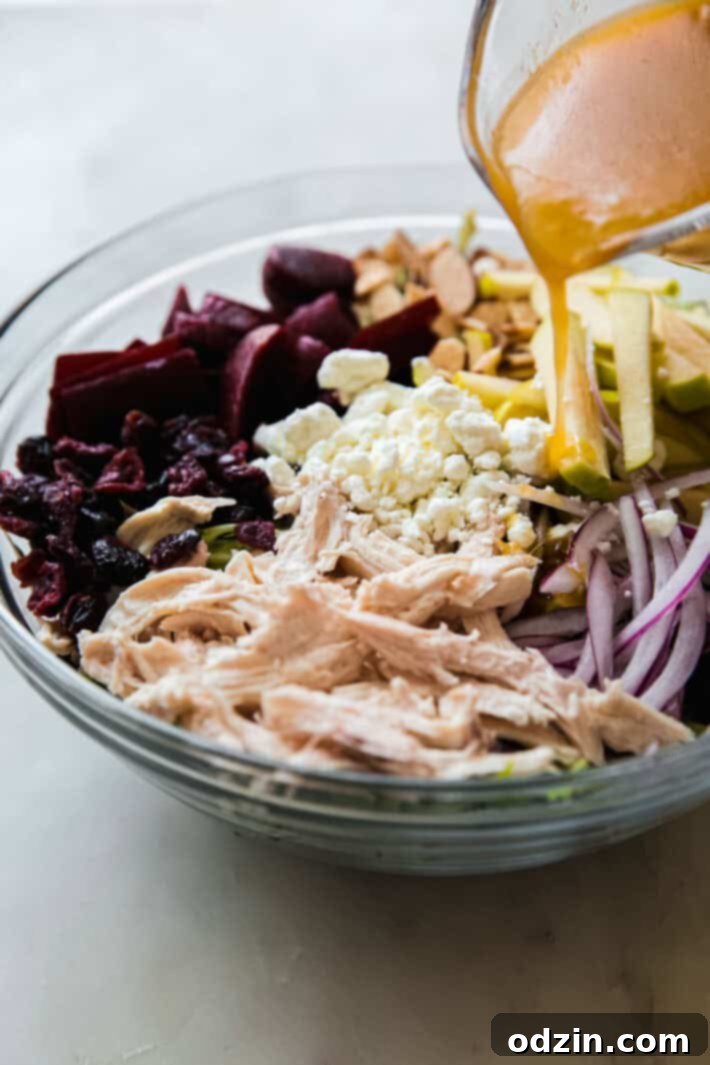 Vibrant Beet Salad with Zesty Citrus Vinaigrette 4 Hand pouring vibrant citrus vinaigrette from a jar onto a large bowl of assembled beet salad