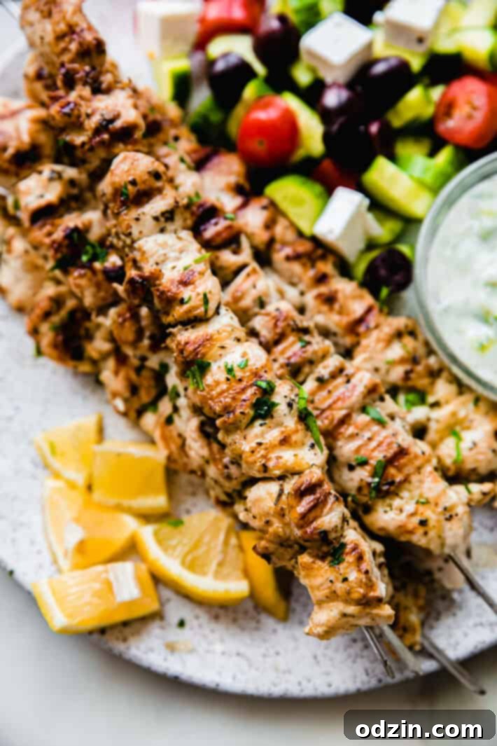 Zesty Greek Chicken Souvlaki Skewers 2 chicken souvlaki skewers on plate with lemon wedges