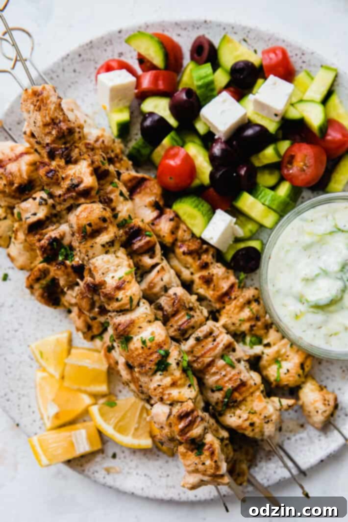 Zesty Greek Chicken Souvlaki Skewers 3 chicken souvlaki on plate with tzatziki and greek salad