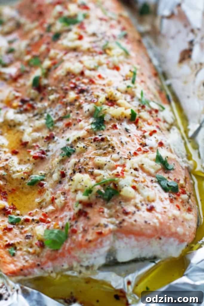 close up of large garlic butter baked salmon filet on foil