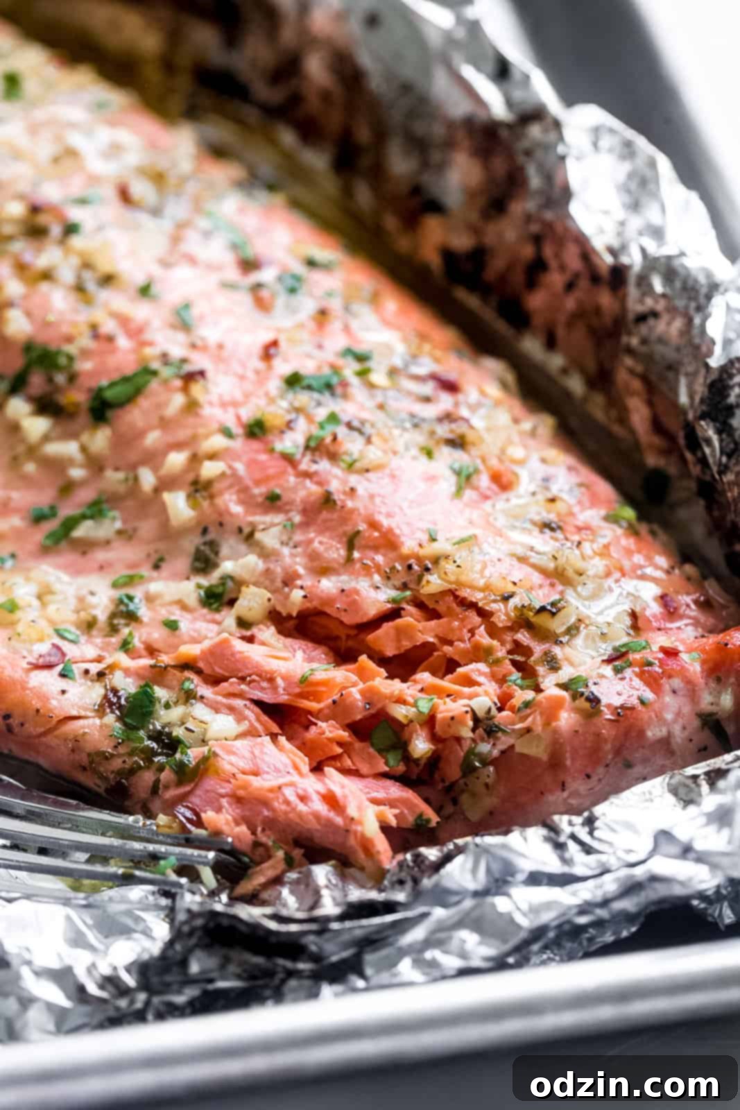 garlic butter baked salmon in foil flaked with a fork to show texture