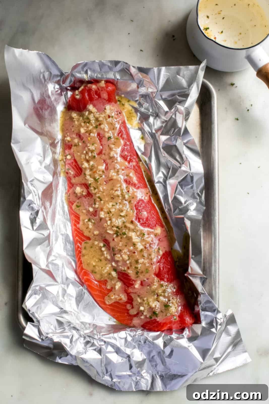 raw salmon filet on foil dressed with lemon garlic butter sauce