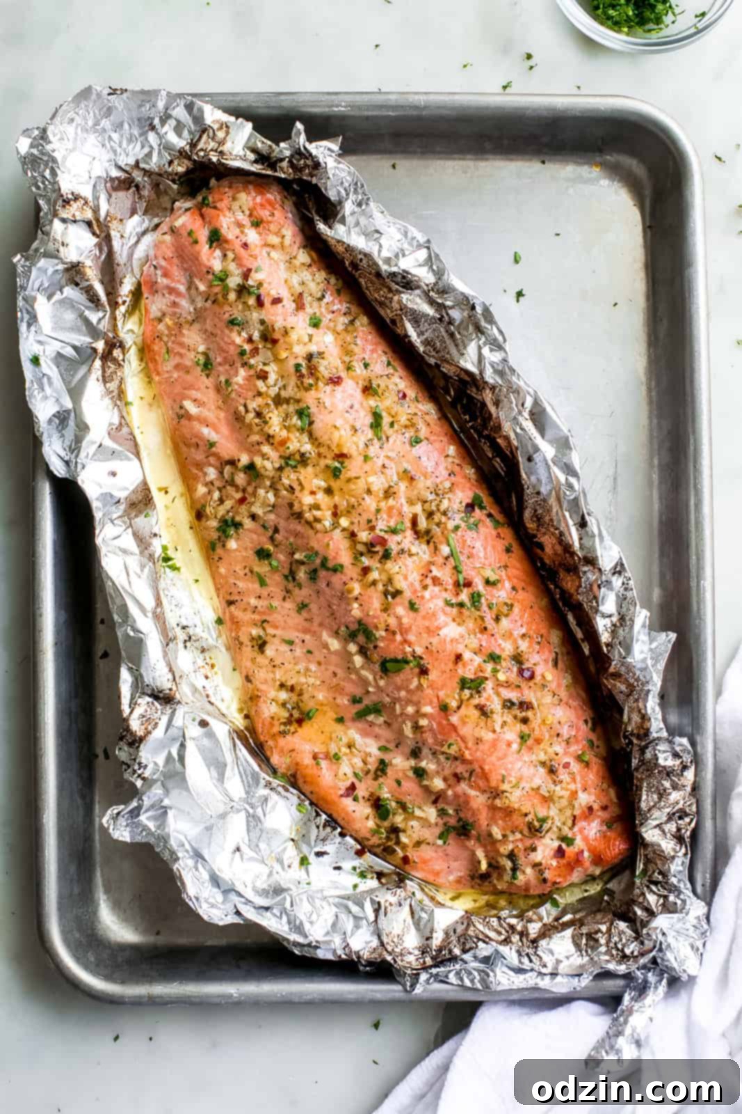 salmon filet prepared in foil on baking sheet pan