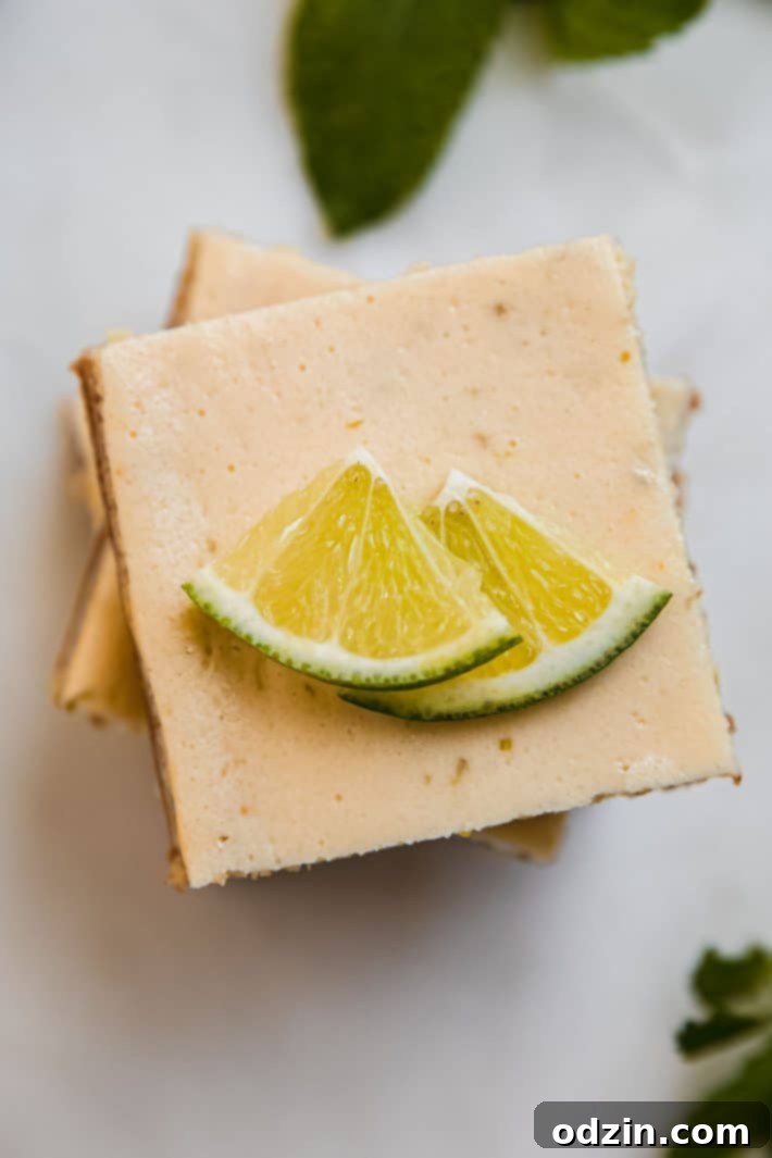 Stacked Key Lime Pie Bars on a marble surface, garnished with fresh lime slices