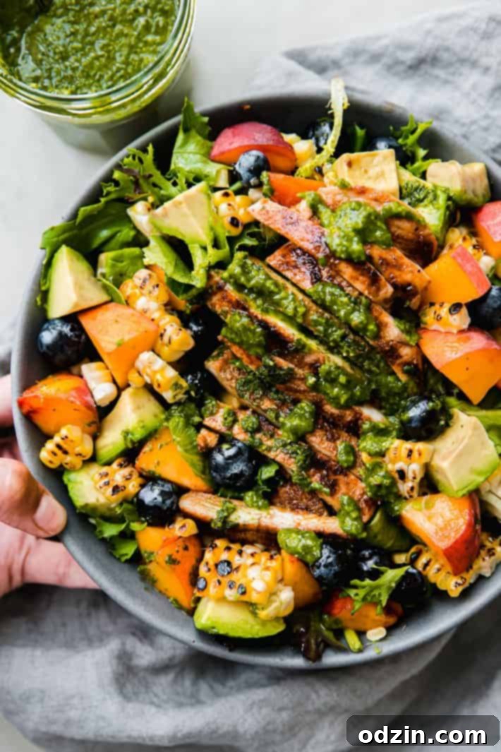 Vibrant Summer Chicken Cobb Salad with peaches, grilled corn, and blueberries on a grey napkin