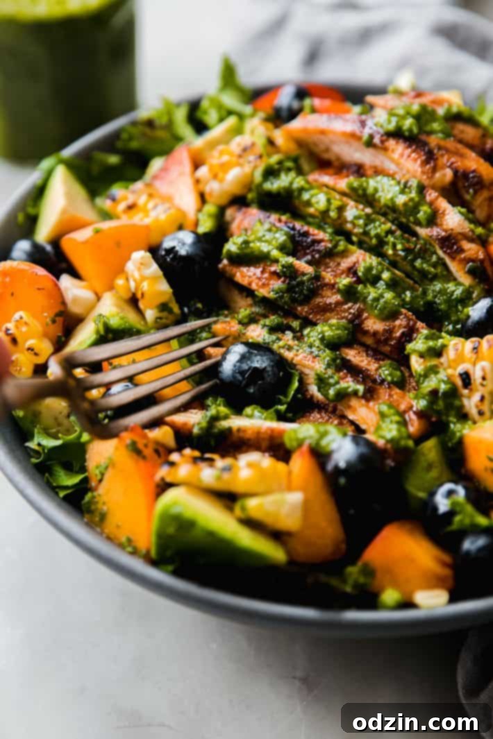 Fork lifting a blueberry from a fresh Summer Chicken Cobb Salad bowl