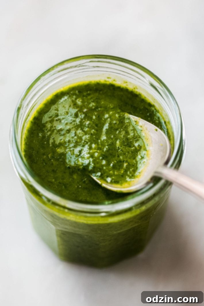 Fresh herb vinaigrette in a glass jar with a small spoon, ready for use