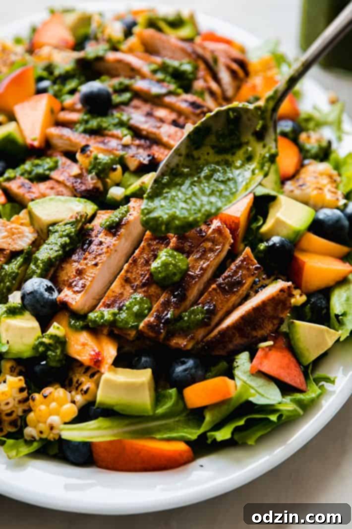 Hand drizzling fresh herb vinaigrette over a colorful Summer Chicken Cobb Salad