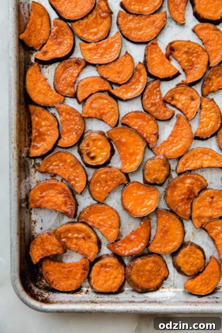 Roasted sweet potatoes spread in a single layer on a sheet pan, showing perfect caramelization.