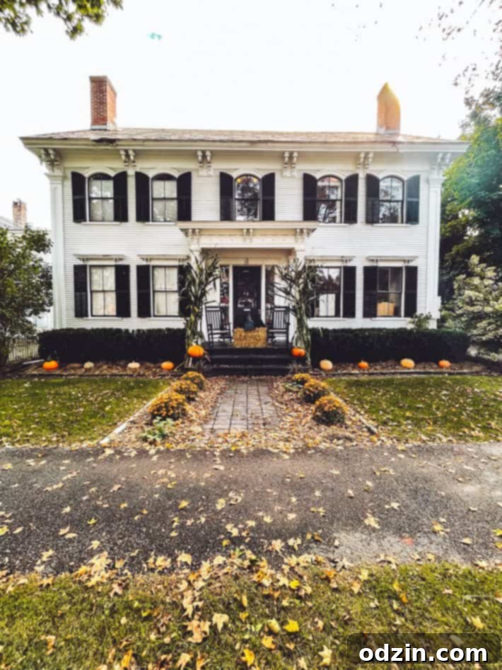Historic manor lined with decorative pumpkins and fall foliage