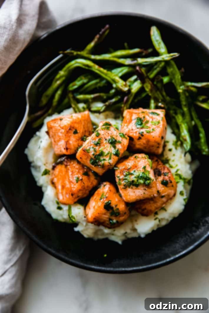 salmon chunks with garlic butter over mashed potatoes with green beans