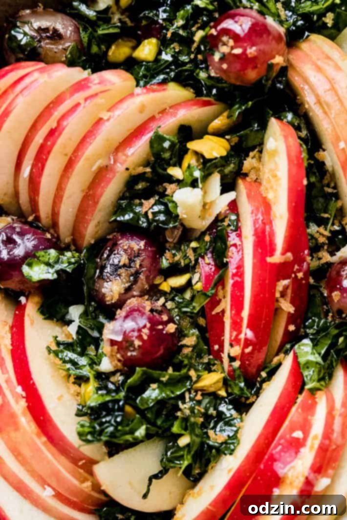 close up of sliced apples charred grapes over lacinato kale with pistachios and panko