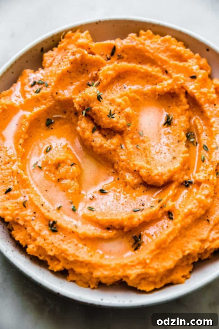 Creamy savory sweet potato mash topped with melted butter and fresh thyme sprigs