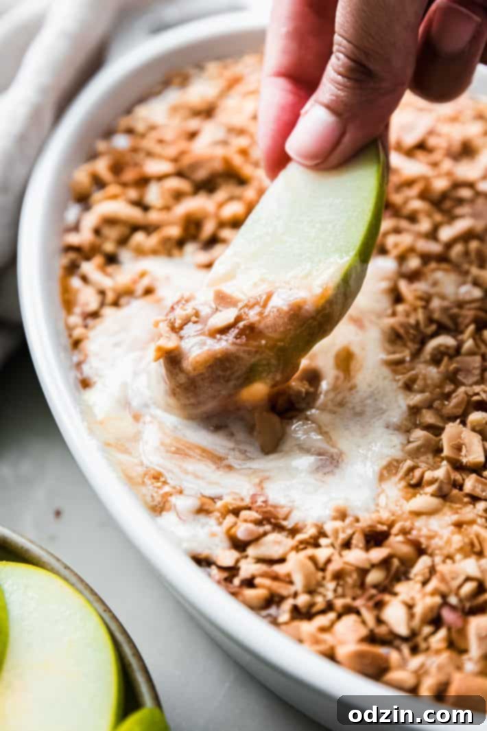 apple slice dipped in caramel with peanuts on top