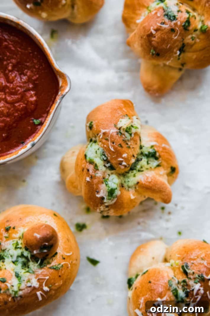 garlic knots on parchment with pizza sauce in bowl