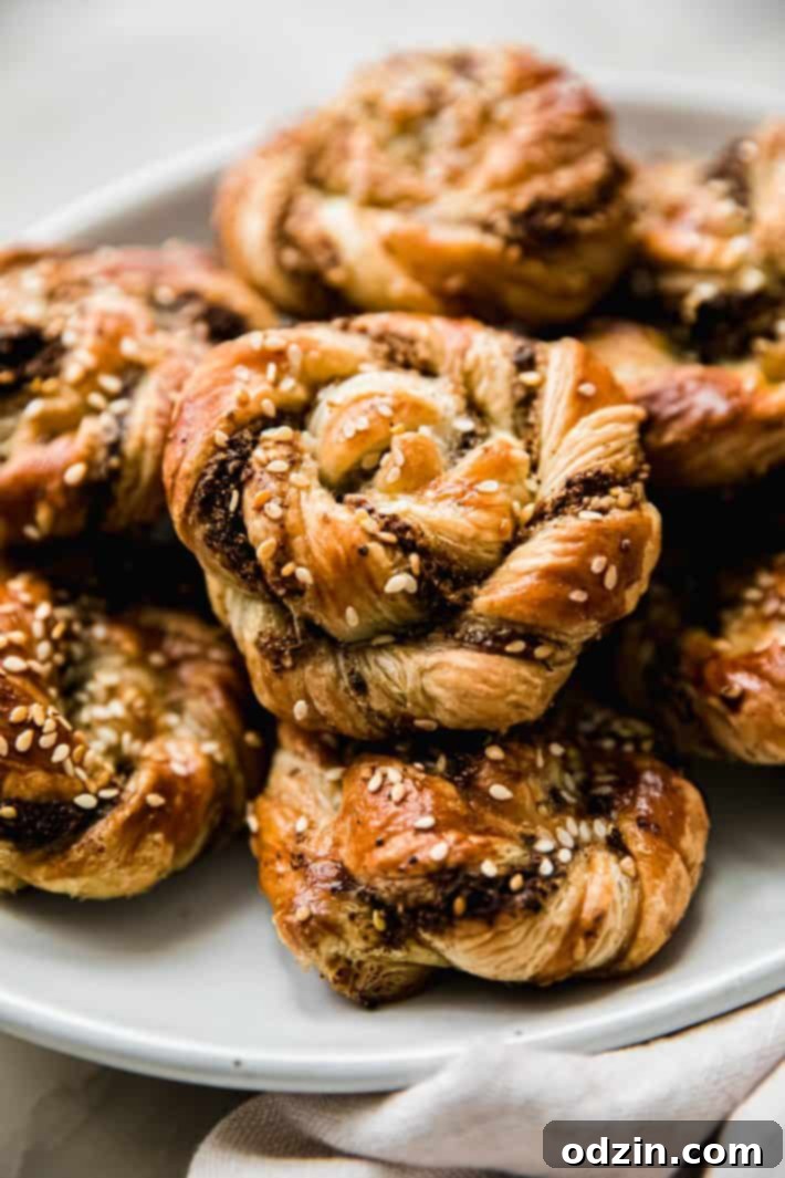 A perspective shot of several finished golden-brown za'atar twist buns arranged on a plate, showcasing their inviting size and appetizing color.