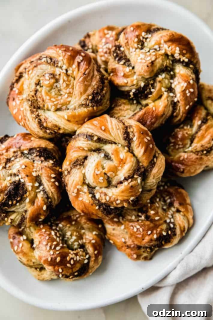 A beautiful arrangement of freshly baked za'atar swirls, adorned with sesame seeds, presented neatly on a white plate, ready to be served as an irresistible appetizer.
