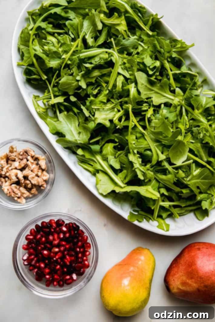 Arugula, walnuts, pomegranate, and pear slices on a platter ready for salad assembly