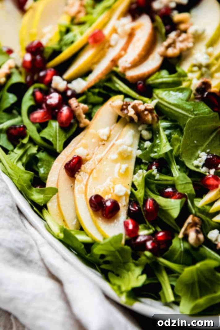 Close up of pear and walnut salad topped with gorgonzola, pomegranate arils, and walnuts