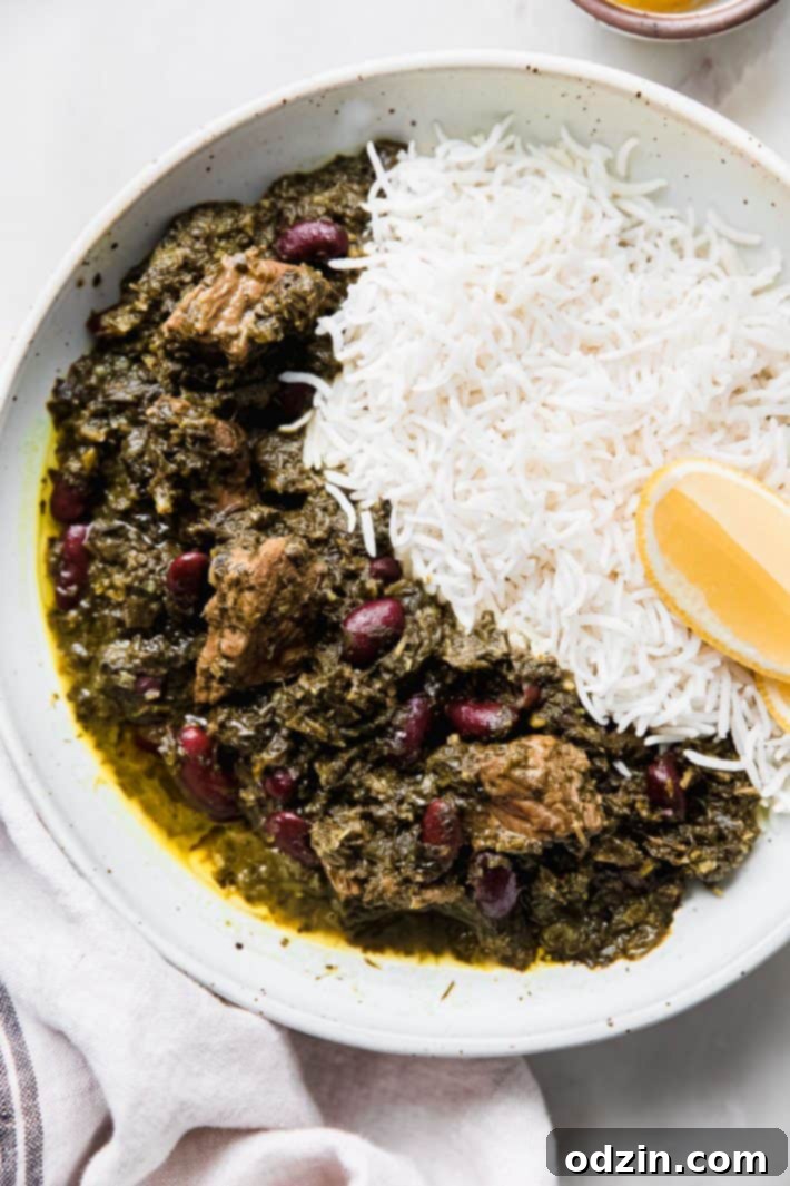 Ghormeh Sabzi served on a plate with fluffy basmati rice, a slice of lemon, and fresh herbs