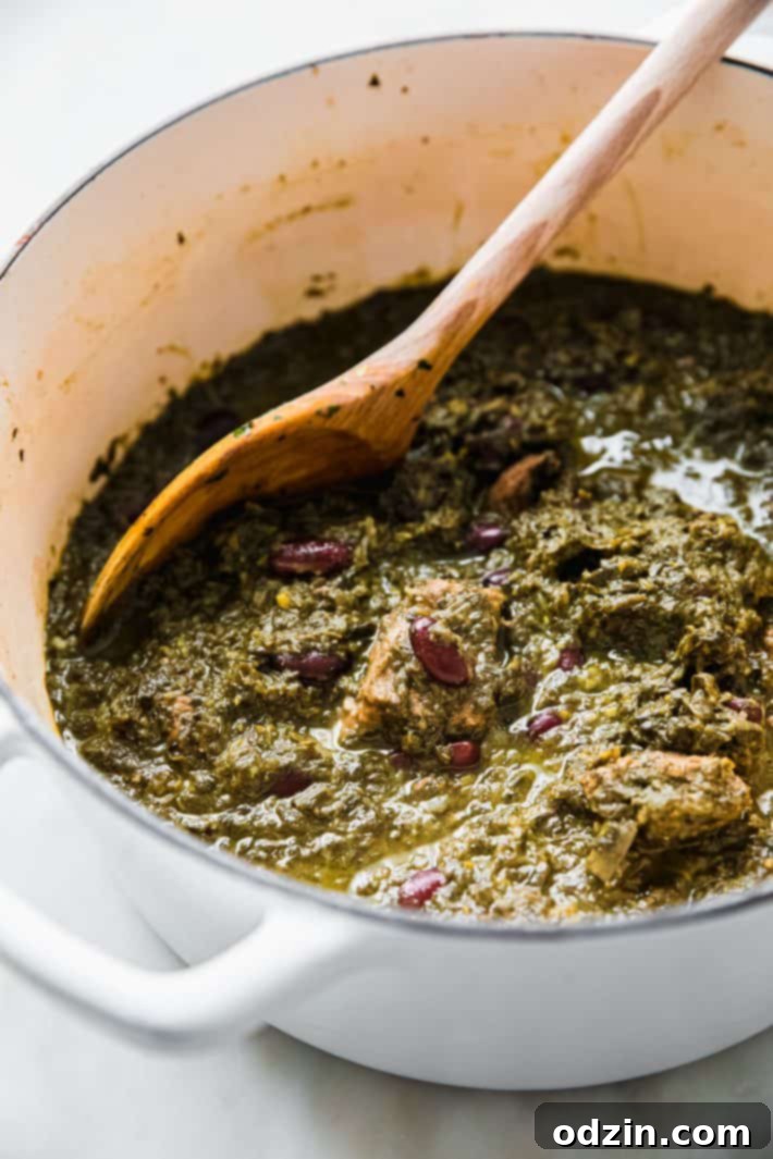 Close-up of Ghormeh Sabzi simmering in a large pot, showing the dark green herbs and tender meat
