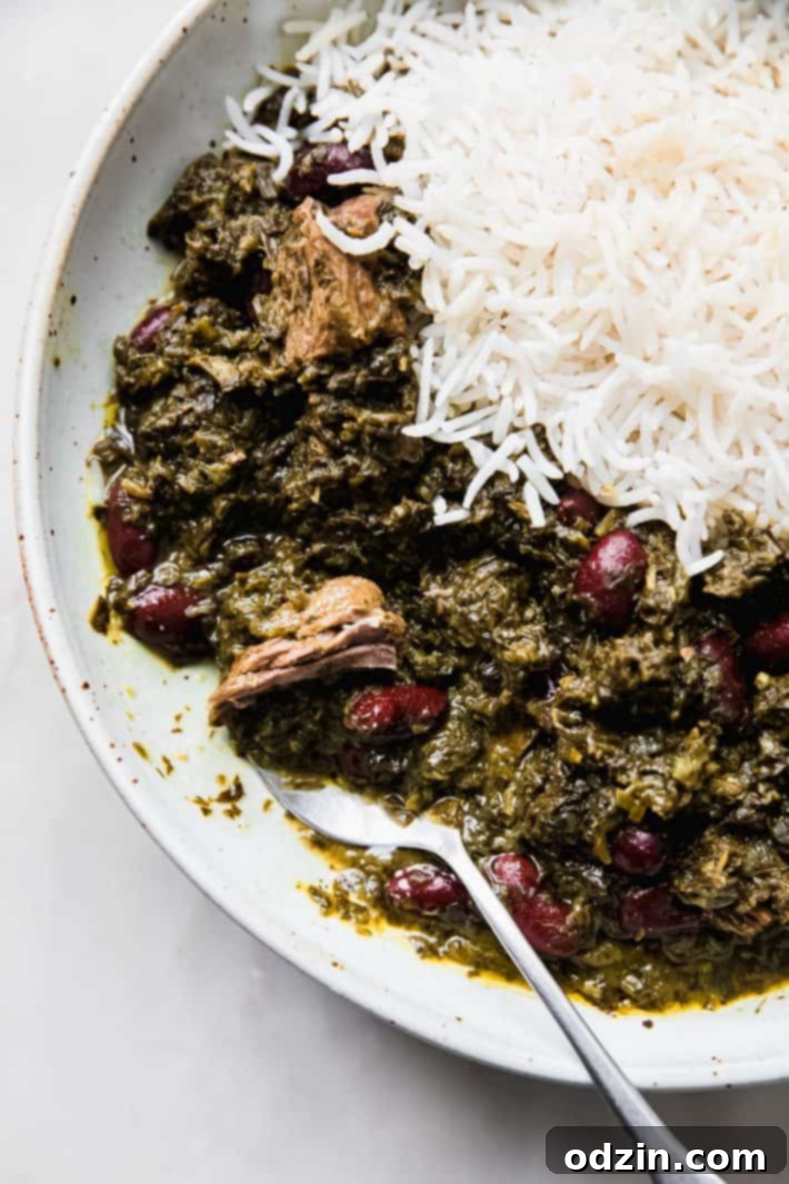 Close-up of Ghormeh Sabzi in a bowl with shredded beef, showing the rich, dark green color of the stew