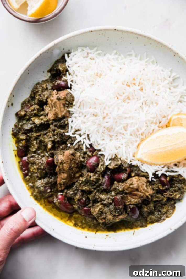 A bowl of Ghormeh Sabzi with rice in a speckled ceramic bowl, garnished with a lime wedge