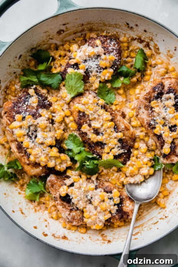 creamed corn chicken in skillet being scooped with a spoon