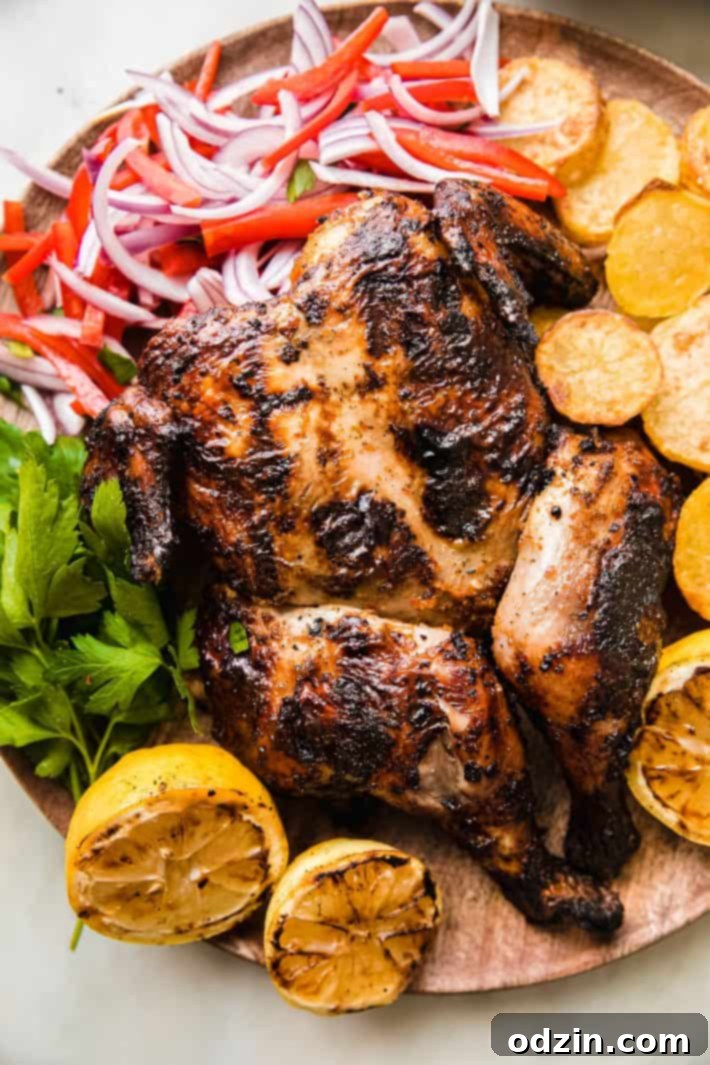 Grilled peri peri chicken served on a rustic wooden board with roasted potatoes and a fresh onion salad