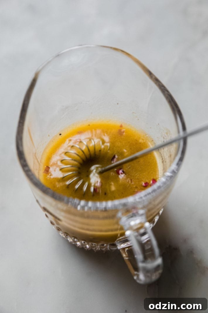 Homemade lemon shallot dressing in a glass measuring cup with a spout, ready to be poured