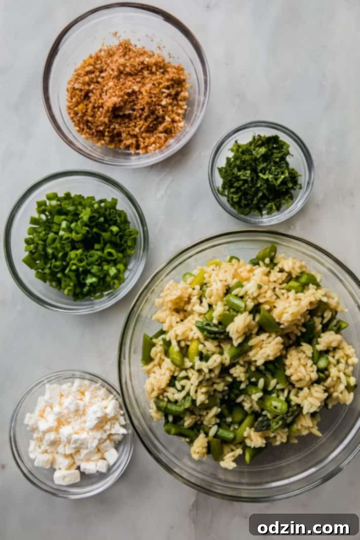 Various fresh salad ingredients, including asparagus, orzo, feta, and fresh herbs, arranged in individual bowls, ready for assembly