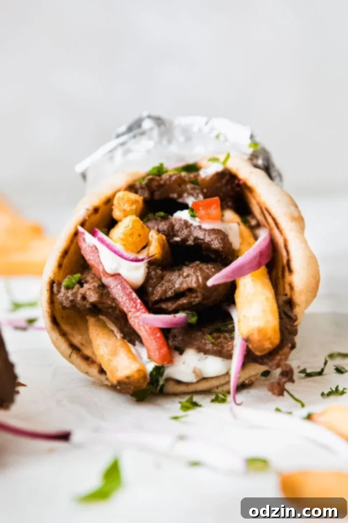 Tender beef souvlaki wrap with golden french fries on parchment paper