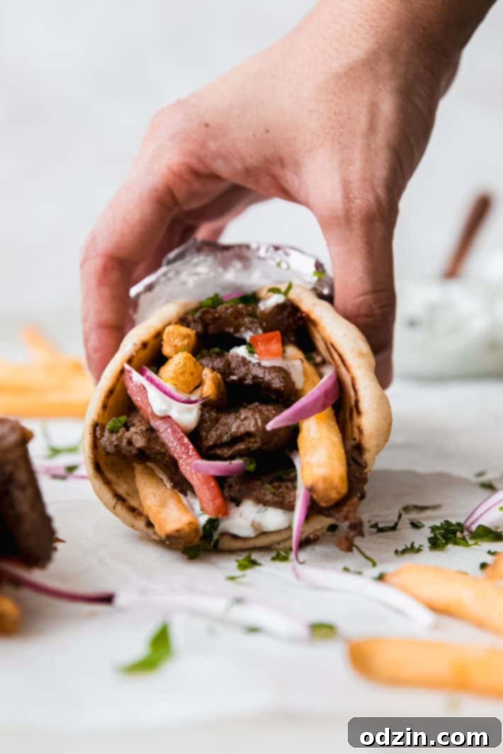 Hand reaching for a delicious beef souvlaki wrap