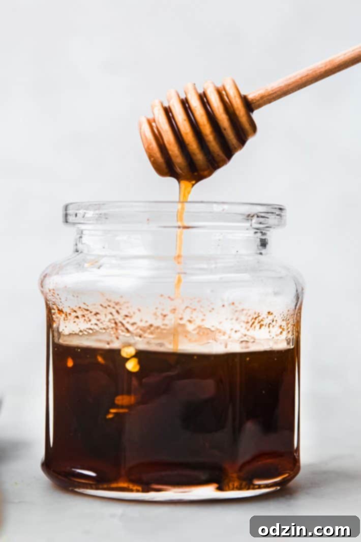 Your Go-To Homemade Hot Honey Recipe for Pizza Tenders and Beyond 2 Hot honey dripping into jar from honeycomb