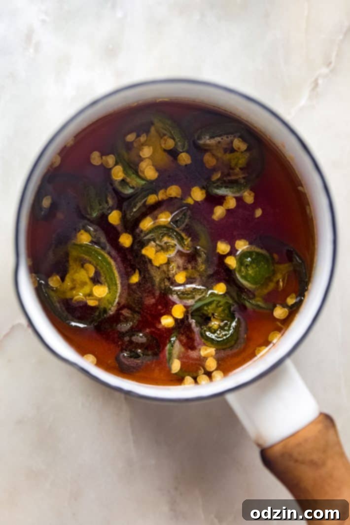 Your Go-To Homemade Hot Honey Recipe for Pizza Tenders and Beyond 3 Hot honey in small saucepan with jalapeño peppers