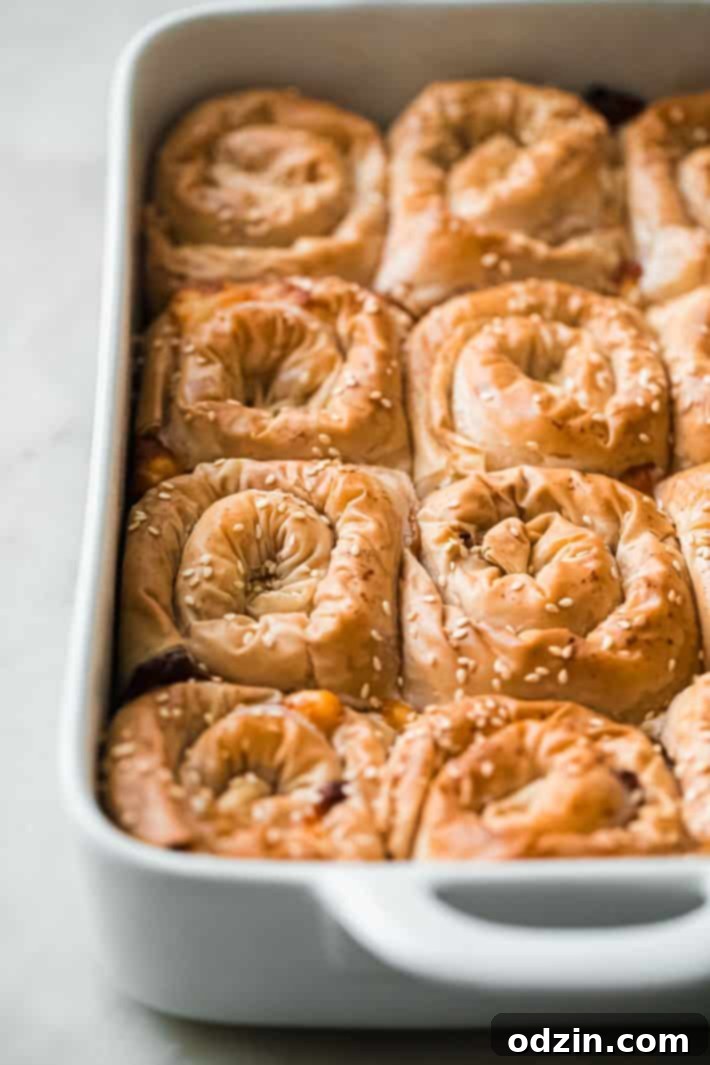 Freshly baked cheese pastries in a baking dish, golden brown and crispy, with sesame seeds on top, ready to be served.