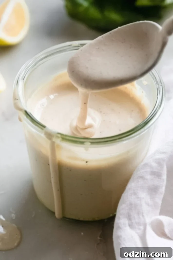 Caesar Dressing in 2 Minutes 2 Creamy homemade Caesar salad dressing dripping from a spoon into a glass jar