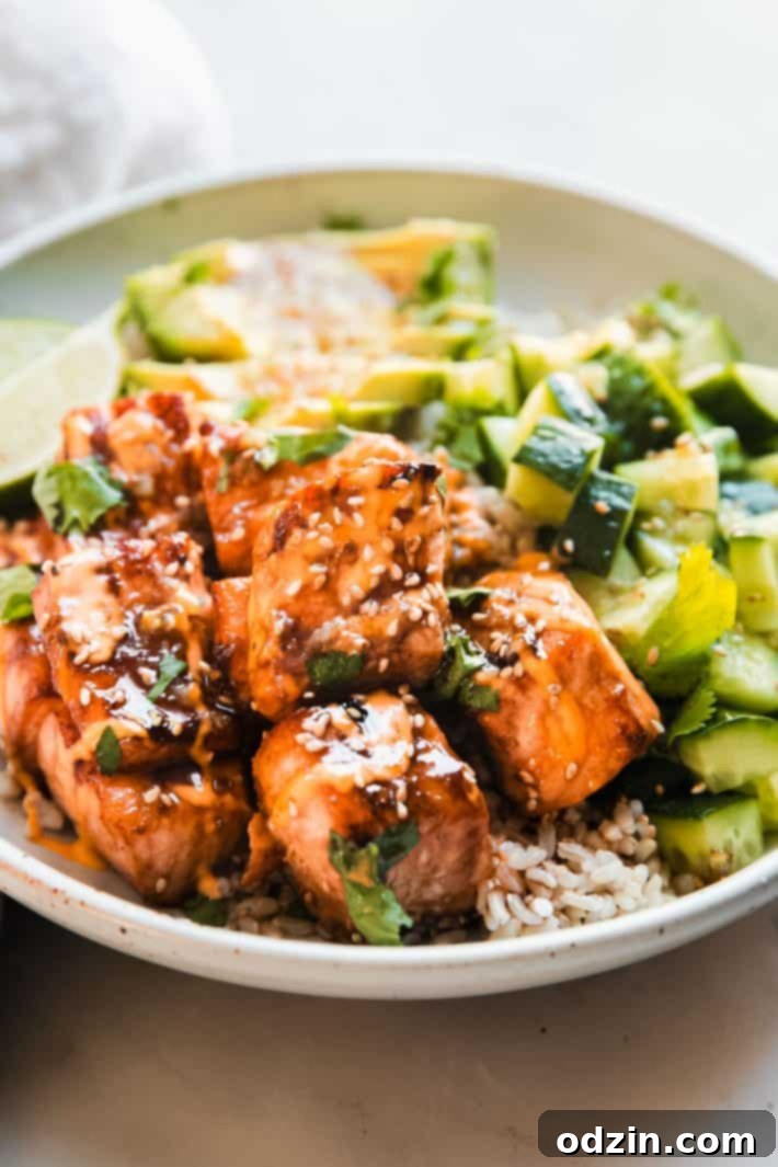 salmon pieces covered with spicy mayo and sesame seeds with cucumbers and rice