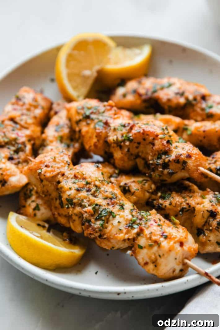 Golden Garlic Parmesan Chicken Skewers 2 garlic parmesan chicken skewers on plate with lemon wedges