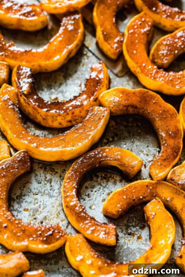 Perfectly caramelized, golden-brown delicata squash slices cooling on a cutting board, ready for serving or garnishing.