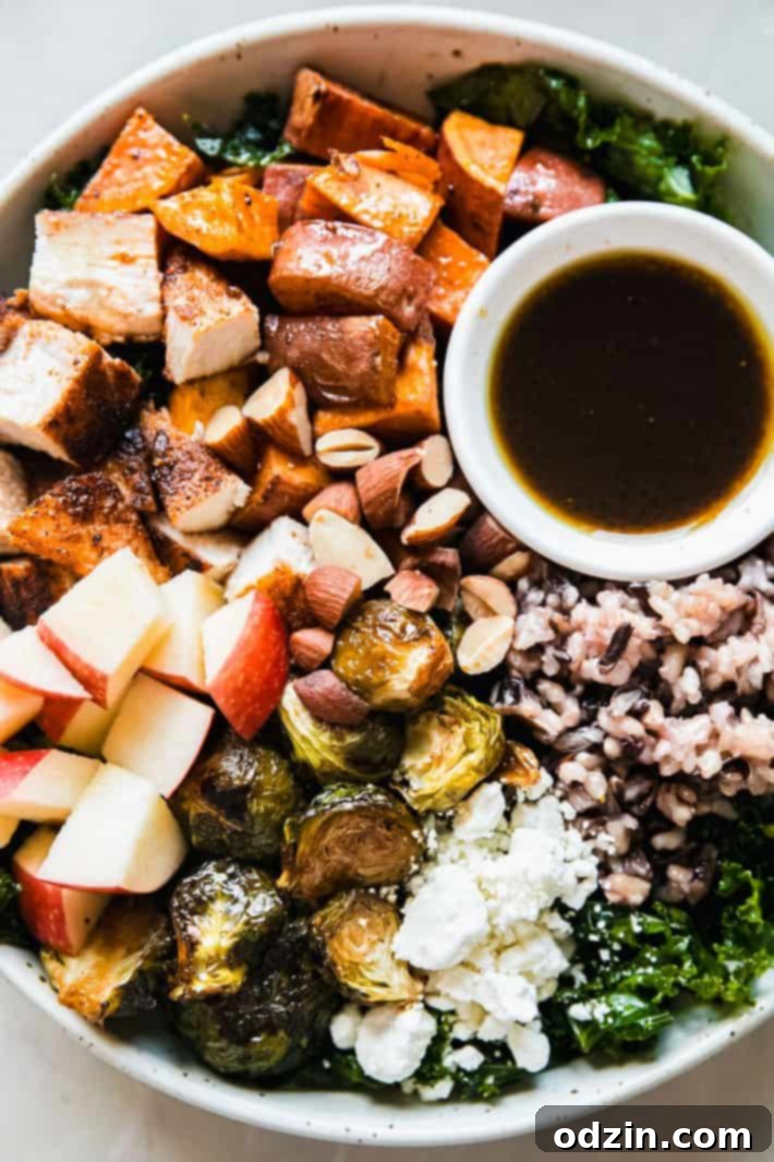Beautifully assembled autumn harvest bowl in a speckled ceramic dish with dressing on the side