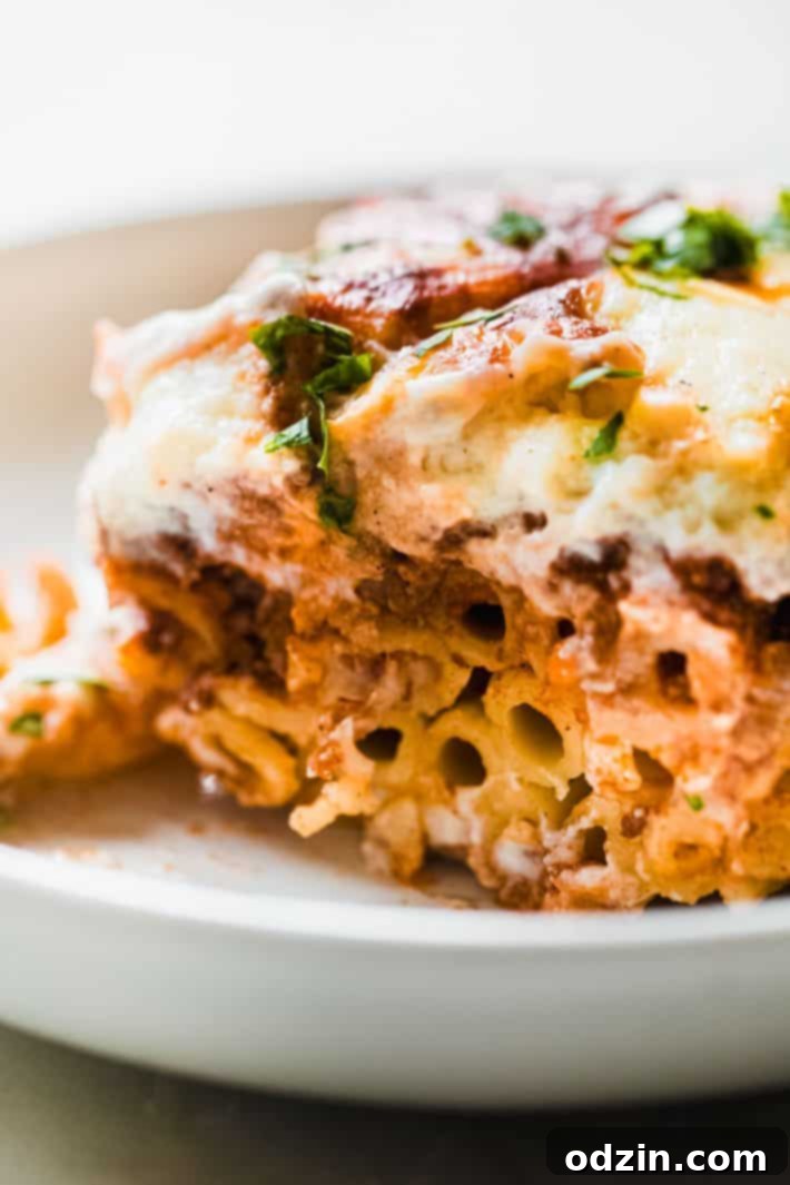 Egyptian Béchamel Macaroni Bake 7 Close-up of a layered pasta bake, showing cooked penne pasta topped with a generous layer of spiced ground meat sauce, ready for the final béchamel topping.