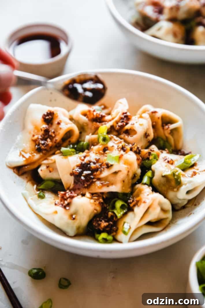 spoon with chili oil drizzling on wontons 