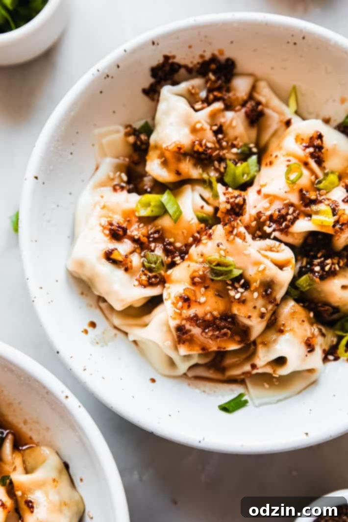 bowl with prepared wontons topped with green onions and chili oil
