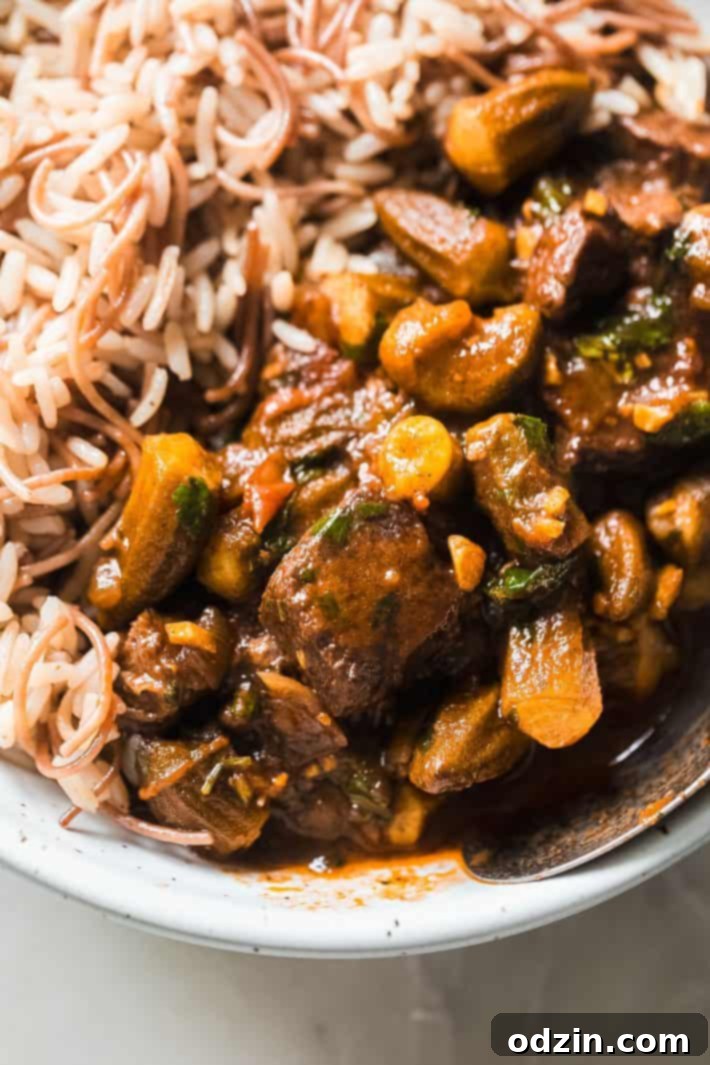 A delightful serving of Bamya, Middle Eastern Okra and Beef Stew, in a bowl alongside fluffy vermicelli rice, perfectly garnished.