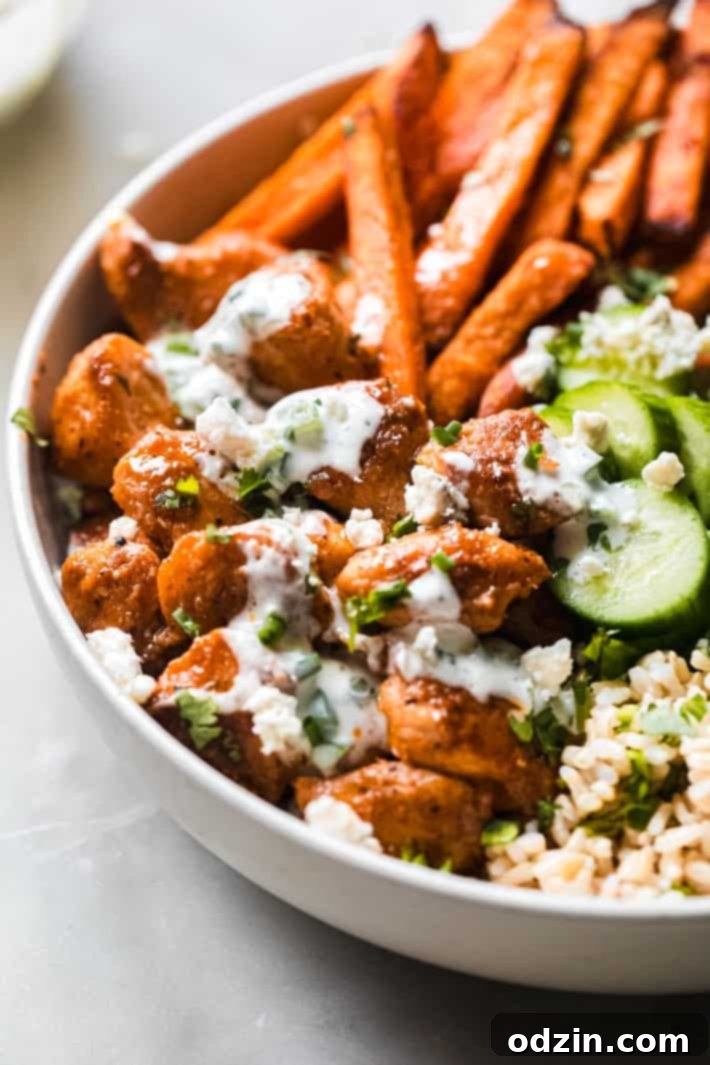 Close-up of cooked buffalo chicken in a pan, coated in sauce with a spoon