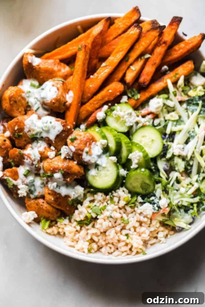 Six buffalo chicken rice bowls neatly arranged, featuring sweet potato fries, slaw, and cucumbers
