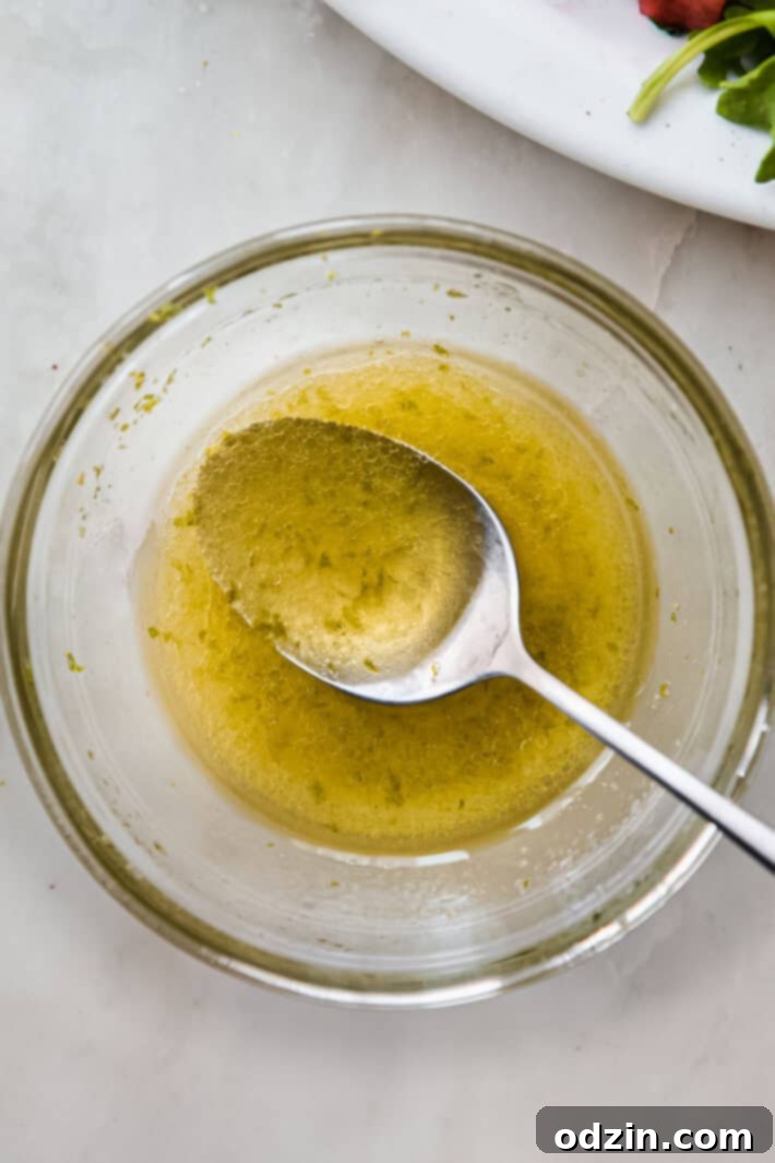 Small bowl of freshly prepared lime dressing with a spoon, ready to be drizzled over salad