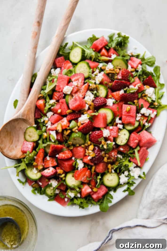 Beautifully dressed watermelon salad arranged on a platter with serving spoons, ready to eat