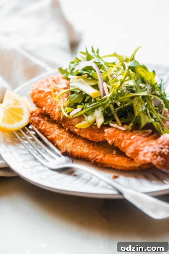 panko breaded chicken cutlets on plate with salad and lemon wedges, ready to serve